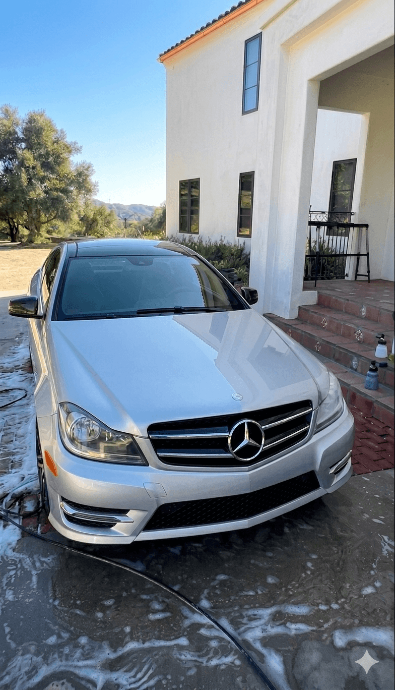 Silver Mercedes-Benz coupe on a wet driveway with soap suds after a mobile hand wash