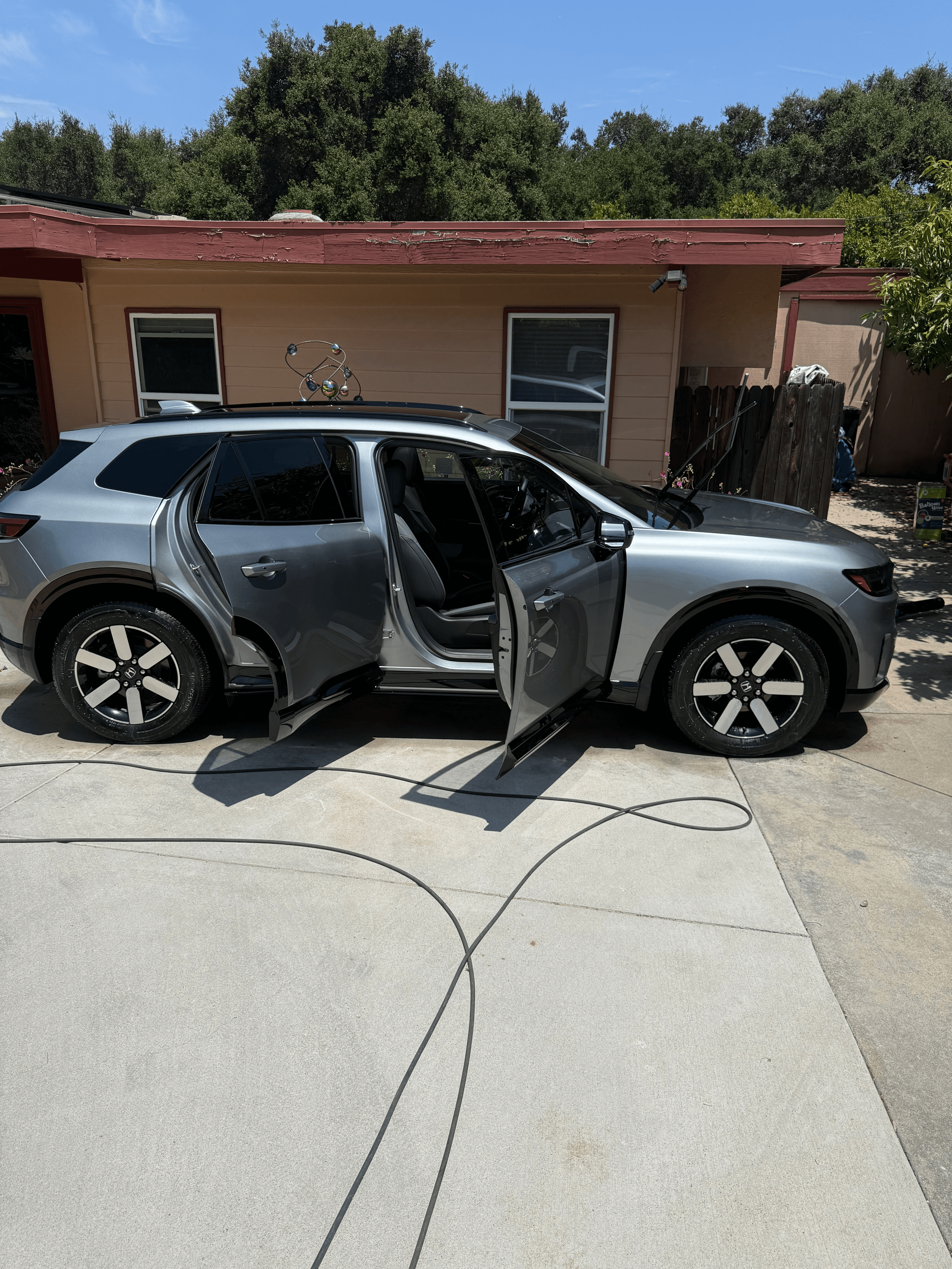 Silver Honda Prologue electric SUV on a concrete driveway with doors open during a mobile exterior detail