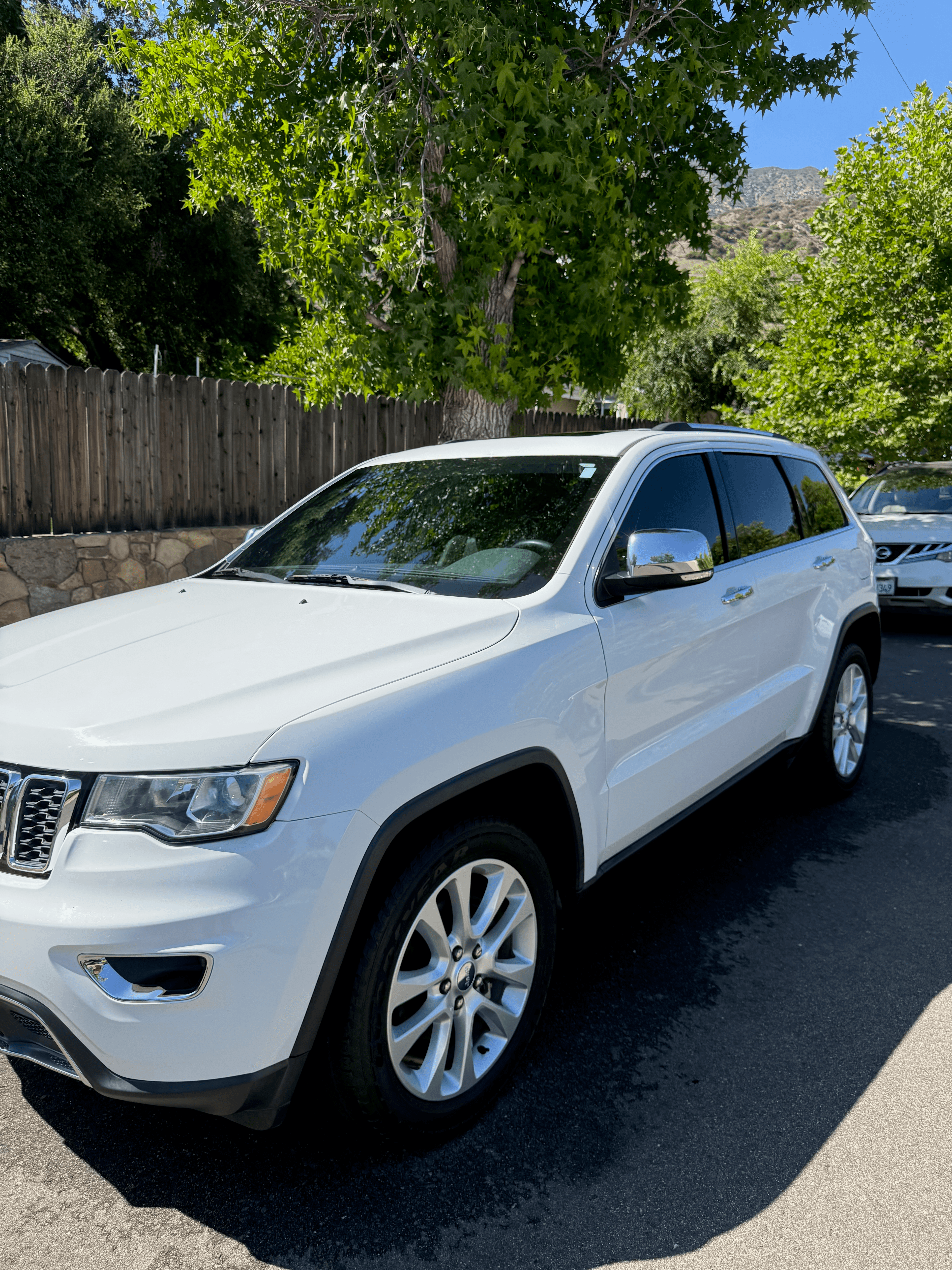 White Jeep Grand Cherokee SUV parked on a shaded residential street with a clean, glossy exterior